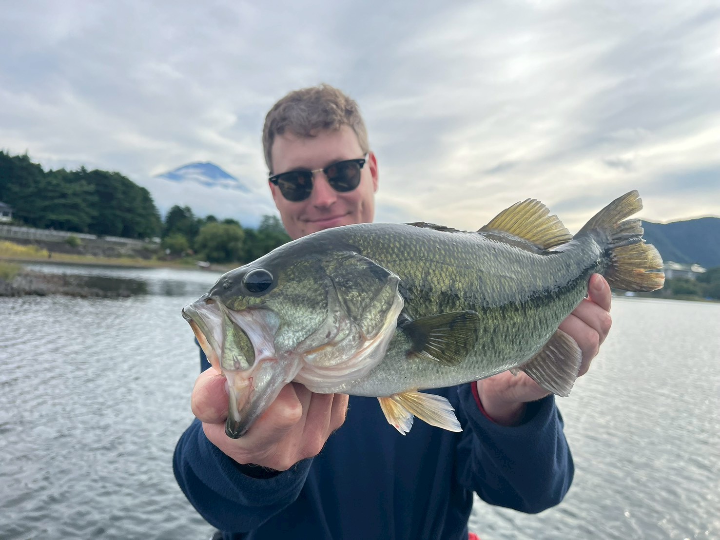 Guest holding a largemouth bass on Lake Kawaguchi with Mt. Fuji in the distance